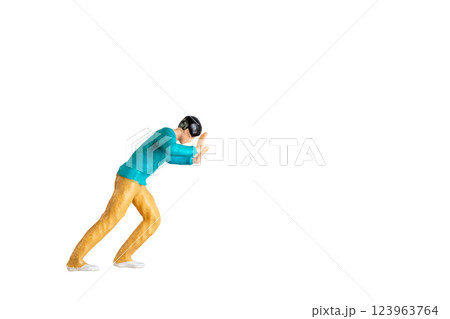 Miniature Figurine Pushing Against Invisible Force isolated on white background with clipping path 123963764