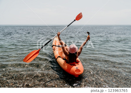 Kayaking Woman Ocean Happy: A woman in a red kayak paddles through the ocean with her arms raised in the air, enjoying a day of kayaking. 123963765