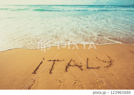The inscription of Italy on the beach of white sand. Gradient color. 123963880