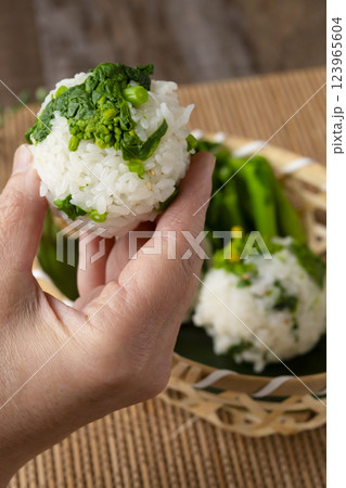 なばなのおにぎりを手に持つ　ナバナのおむすびを手で持つ 123965604