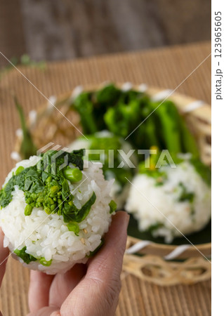 なばなのおにぎりを手に持つ　ナバナのおむすびを手で持つ 123965605