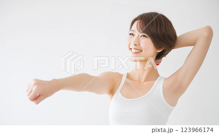 白い背景でストレッチをする女性。片腕を前に出し、片腕を上に上げ伸ばしている。 123966174