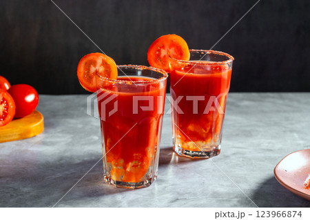 Two vegetable shaken cocktails in glass on dark grey background. Red tomato cocktail. Served with tomato slice. Vegan menu. Two vegetable shaken cocktails in glass on dark grey background. Red tomato cocktail. Served with tomato slice. Vegan menu. 123966874