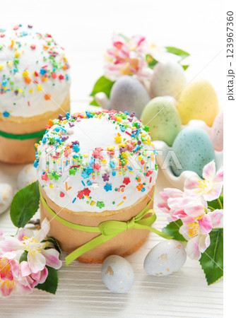 Delicious easter cakes decorated with colorful sprinkles and eggs on white table 123967360