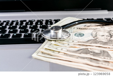 Stethoscope on top of money on laptop keyboard. Stethoscope on dollar bills on top of laptop keyboard Stethoscope on top of money on laptop keyboard. Stethoscope on dollar bills on top of laptop keyboard 123969058