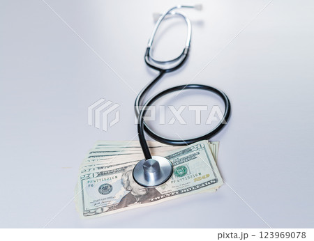 Stethoscope on dollar bills isolated. Stethoscope on top of dollar bills isolated, Medical cost concept Stethoscope on dollar bills isolated. Stethoscope on top of dollar bills isolated, Medical cost concept 123969078