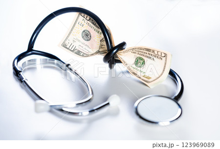 Stethoscope tied with dollar bills. High cost of medical health with stethoscope. Stethoscope wrapped around money isolated 123969089