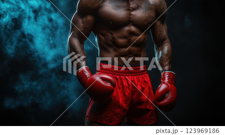 muscular man in red boxing gloves and shorts stands confidently with smoke in background 123969186