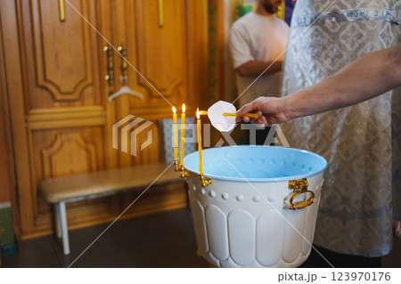 Three lit church candles on the baptismal font in a wooden church.  123970176