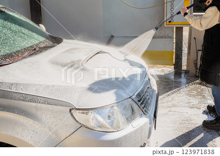 Woman Using High-Pressure Washer to Clean a Dirty SUV at a Self-Service Car Wash 123971838