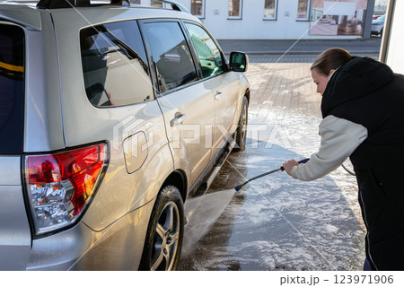 Woman Using High-Pressure Washer to Clean a Dirty SUV at a Self-Service Car Wash Woman Using High-Pressure Washer to Clean a Dirty SUV at a Self-Service Car Wash 123971906