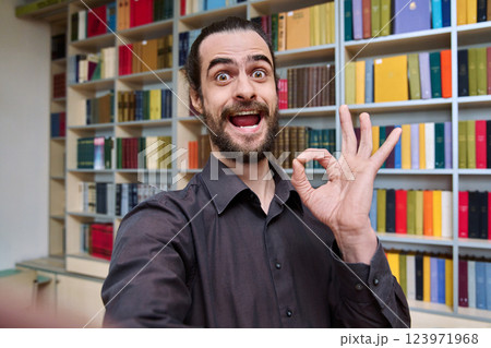 Selfie photo portrait young 30s positive man inside library showing ok gesture 123971968