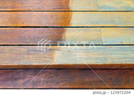 Close-up of a wooden deck showing the process of restoration with a half-stained surface 123972204