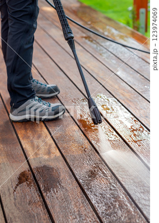 cleaning terrace with a power washer - high water pressure cleaner on wooden terrace surface cleaning terrace with a power washer - high water pressure cleaner on wooden terrace surface 123974069