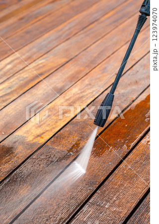 cleaning terrace with a power washer - high water pressure cleaner on wooden terrace surface cleaning terrace with a power washer - high water pressure cleaner on wooden terrace surface 123974070