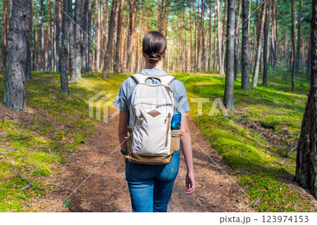 A young woman with a backpack walks through the forest. Hiking in the woods. A young woman with a backpack walks through the forest. Hiking in the woods. 123974153
