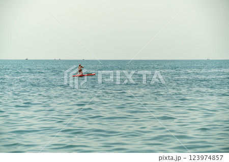 Paddleboarder Enjoying Calm Waters on a Peaceful Afternoon Paddleboarder Enjoying Calm Waters on a Peaceful Afternoon 123974857