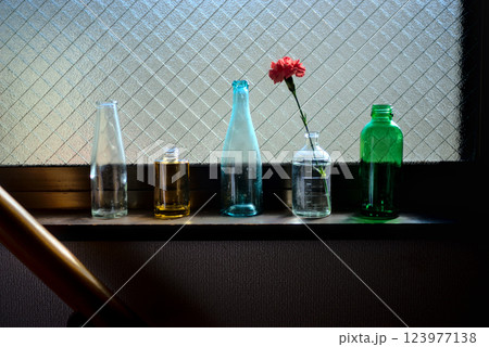 「窓辺で陽光を浴びる空瓶たちの静寂な美 123977138
