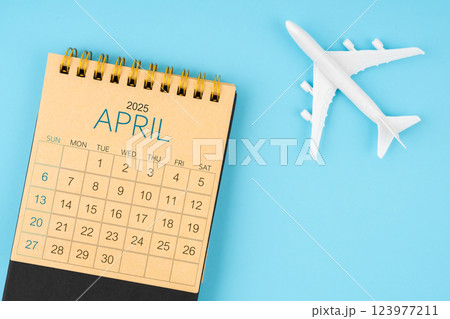 April 2025 calendar and airplane toy on blue background. April 2025 calendar and airplane toy on blue background. 123977211