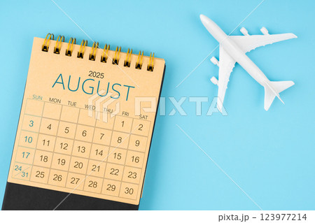 August 2025 calendar and airplane toy on blue background. 123977214