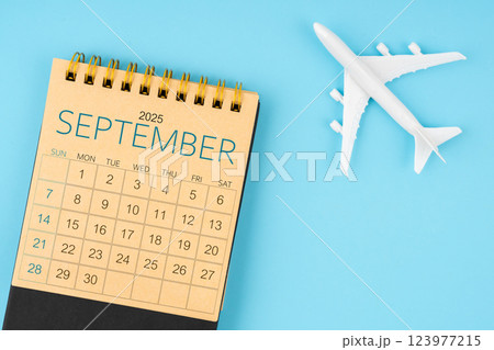 September 2025 calendar and airplane toy on blue background. 123977215