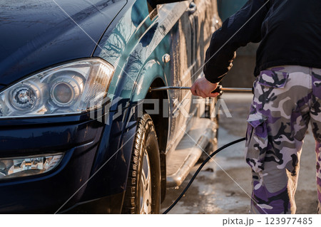 Person Washing Dark Blue SUV Car Using High Pressure Washer at Outdoor Self-Service Car Wash Station Person Washing Dark Blue SUV Car Using High Pressure Washer at Outdoor Self-Service Car Wash Station 123977485