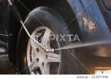 Close-up of Pressure Washing Equipment Spraying Water Cleaning Car Tire and Rim 123977496