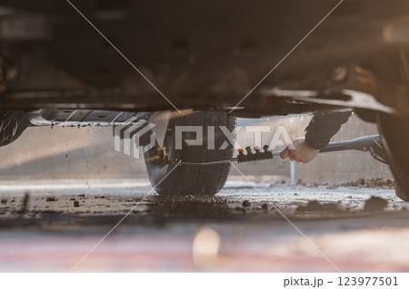 Close-up View Under Vehicle Showing Pressure Washer Cleaning Dirt From Tire Surface 123977501