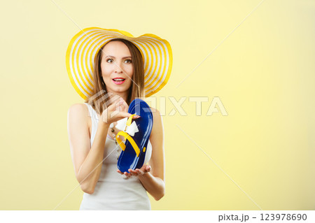 Woman in big yellow summer hat holds flip flops Woman in big yellow summer hat holds flip flops 123978690