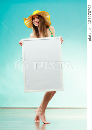 Woman in bikini holds blank presentation board. 123978702
