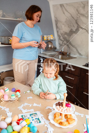 Mid shot of little girl plays with wooden rabbit, sitting at table decorated for spring Easter Mid shot of little girl plays with wooden rabbit, sitting at table decorated for spring Easter 123981146