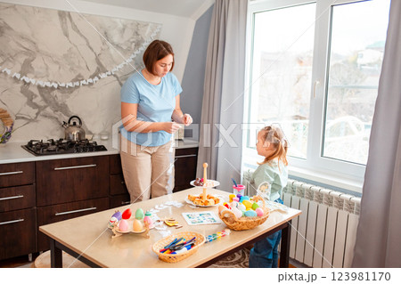 Wide shot of little girl and teacher are making festive decorations for spring Easter 123981170