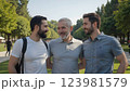 Three cheerful men enjoying sunny friendship moment outdoors, genuine friendship bonding visible between smiling friends, relaxed friendship atmosphere surrounded by green trees during day. 123981579