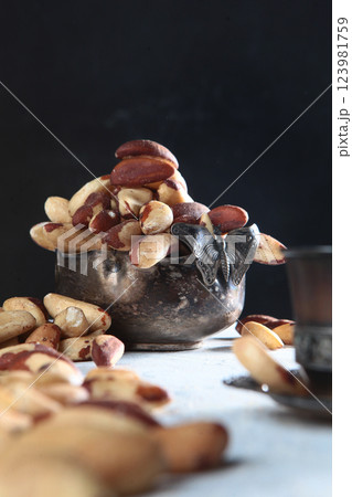 Brazil nut in a metal basket on a black background. Side view. Vintage tableware. Natural protein and antioxidant. Vertical photo. 123981759