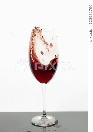 Red wine in glass. Splashes of red wine. Transparent glass with wine or juice on white background. Isolated object. 123981766