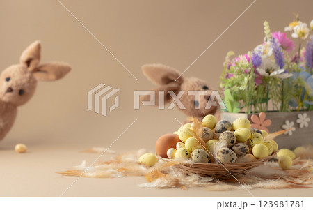 Easter eggs, feathers, spring flowers, and toy bunny on a beige background. 123981781
