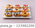 donuts with powdered sugar and various toppings on a white plate on a pale purple background. Top view . Copy space 123982200