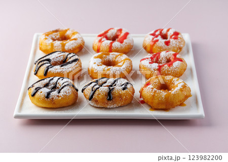 donuts with powdered sugar and various toppings on a white plate on a pale purple background. Top view . Copy space 123982200