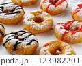 A group of donuts with powdered sugar and various toppings on a white plate close-up 123982201