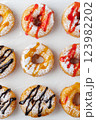 A group of donuts with powdered sugar and various toppings on a white plate close-up. Top view 123982202