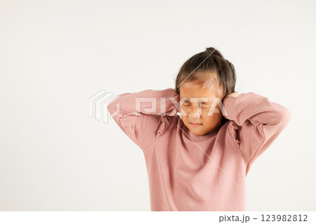 Asian young kid girl closed ears with hand palm and close eyes, studio shot isolated on white background, portrait kindergarten child covers ears from music loud noise with copy space, Deaf concept 123982812