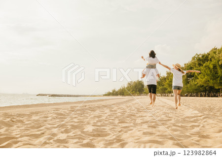 Happy family in holiday. Father, Mother and kids having fun together shoulder ride and running on summer beach, Parents carrying children on neck, family is enjoying their summer in sunset time Happy family in holiday. Father, Mother and kids having fun together shoulder ride and running on summer beach, Parents carrying children on neck, family is enjoying their summer in sunset time 123982864