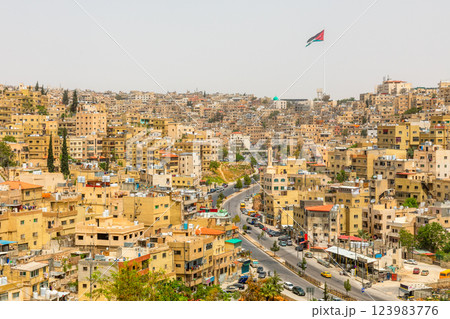 Lots of residential houses densily scattered on the hills in the downtown of Amman city with national flag waving on the wind, Kingdom of Jordan 123983776