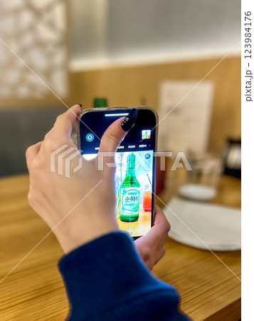 Woman using a smartphone to take a photo of a bottle of beer. Woman using a smartphone to take a photo of a bottle of beer. 123984176