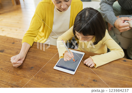 タブレット学習をする孫を見守る祖父母 タブレット学習をする孫を見守る祖父母 123984237