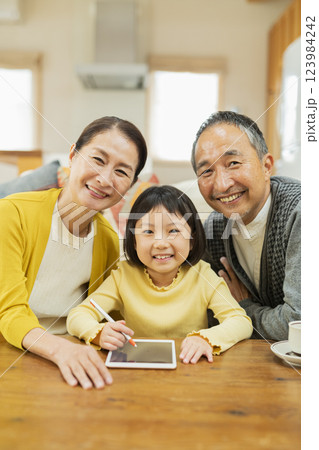タブレット学習をする孫を見守る祖父母 タブレット学習をする孫を見守る祖父母 123984242