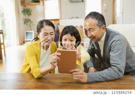 タブレット学習をする孫を見守る祖父母 123984254