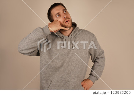 The man positions his hand like a phone near his ear, pretending to make a call. His relaxed demeanor suggests a fun and informal moment. The gesture conveys creativity and humor. 123985200