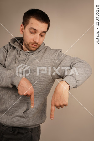 Pointing down with both hands, the man focuses attention on a lower point. His precise gesture is engaging and intentional. The image conveys clarity and purpose. Pointing down with both hands, the man focuses attention on a lower point. His precise gesture is engaging and intentional. The image conveys clarity and purpose. 123985220