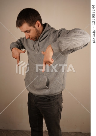 His precise gesture is engaging and intentional. The image conveys clarity and purpose. Pointing down with both hands, the man focuses attention on a lower point. 123985244